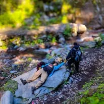Participantes descansando junto a un arroyo durante una experiencia al aire libre