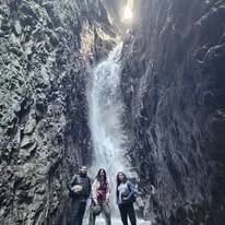 Excursionistas frente a una cascada entre paredes rocosas